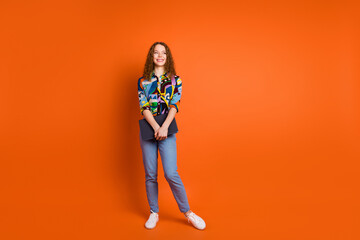 Photo of pretty adorable nice girl wear stylish clothes look empty space isolated on vivid orange color background