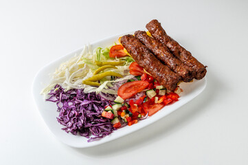 Plate of seekh kebab with vegetables centered and isolated on white background 