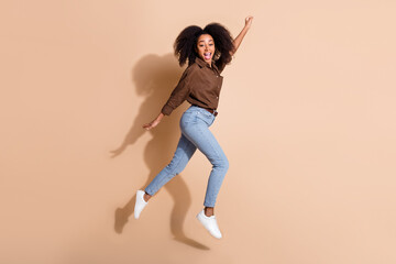 Full length photo of overjoyed impressed girl wear brown blouse flying to empty space hold fist up...