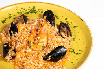 Seafood risotto, a typical Italian dish also called risotto alla pescatora. Rice in a yellow plate...