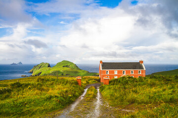 View of red cottage in St. Finian's Bay with Puffin Island in the background and Skelligs in the...