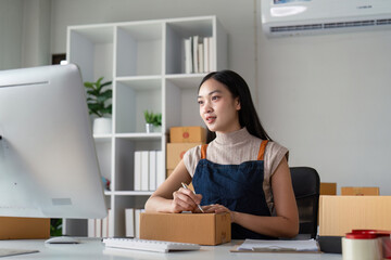 Young business woman asian working online ecommerce shopping at her shop. Young woman sell prepare parcel box of product for deliver to customer. Online selling - obrazy, fototapety, plakaty