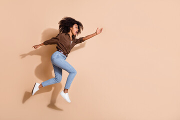 Fototapeta na wymiar Full length photo of impressed girl wear brown blouse running stretching hand to object in empty space isolated on pastel color background