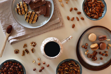 Cup of tea or coffee, cookies, macaroons, chocolate, various nuts and cocoa powder on white...