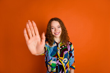 Photo of adorable positive cute girl wear stylish print clothes showing palm hand isolated on vivid orange color background