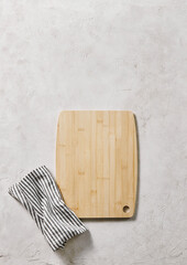 Wooden cutting board on the decorative table, view from above, napkin, empty, textured background.