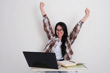 Female college student showing happy relieved expression when sitting on her study desk