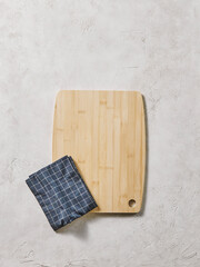 Wooden cutting board on the decorative table, view from above, napkin, empty, textured background.