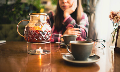 Jug of tea on rack with burning candle.