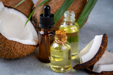 Bottle of coconut oil and fresh coconuts with palm leaf