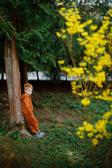 Photo of little red-haired boy 3 years old runs in flowering meadow, child walks in fresh air, rear...