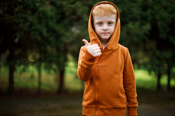 Red-haired handsome boy in a hood shows thumb up. Smile © Iryna Savchuk