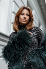 Beautiful red-haired girl in a fashion leopard T-shirt with a shaggy jacket on the street in the city