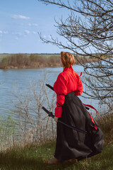 A woman with short red hair in a black and red hanfu and two katanas looks into the distance...