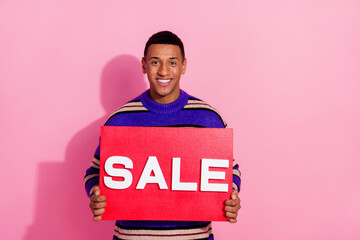 Photo of toothy funky guy dressed striped pullover smiling holding sale card empty space isolated...