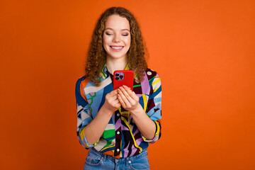 Photo of pretty cute girl blogger wear trendy print clothes hold device isolated on vibrant orange color background