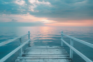 A peaceful wooden pier extends into the ocean, leading to a stunning horizon lit by the hues of...