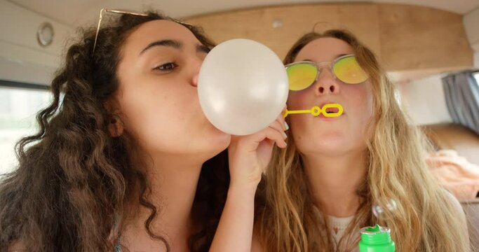Friends, road trip and blow bubbles or bubblegum for holiday or vacation and travel fun, silly and playful. Young group of people or gen z with silly games in car or van for transport and adventure