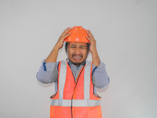 Scared asian  man builder worker man is holding his hands on his head with wide open mouth isolated on white background.