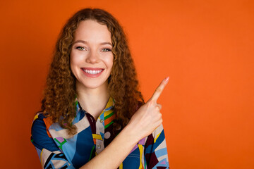Photo of pretty adorable cheerful girl wear stylish print clothes feedback empty space isolated on vibrant orange color background