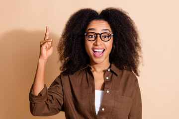 Photo of clever girl with perming coiffure wear brown blouse in glasses raising finger have idea...