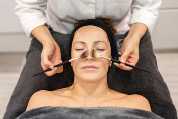 Beautician applying cosmetics on client in beauty salon - 796512561