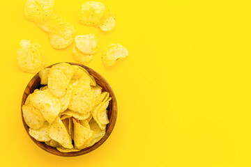Wooden bowl of crispy potato chips, top view. Fast food and snack background