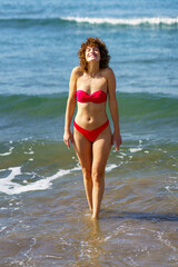 Slim woman in bikini walking in ocean water