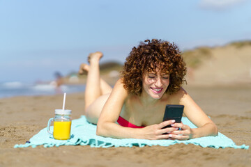 Happy woman with smartphone and juice on beach - 796515126