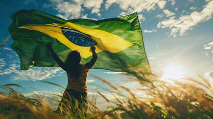 A person holding the Brazilian flag, viewed from the back, symbolizing patriotism and national pride. - obrazy, fototapety, plakaty