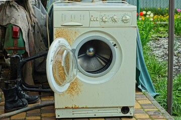 one white old  iron rusty broken open glass door electric modern discarded washing machine stands...