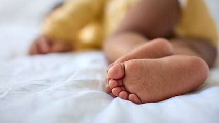 Close Up Of Feet Of Sleeping Baby Girl Lying On Parent's Bed At Home