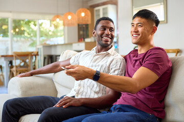 Same Sex Male Couple Or Friends On Sofa At Home Watching TV Together