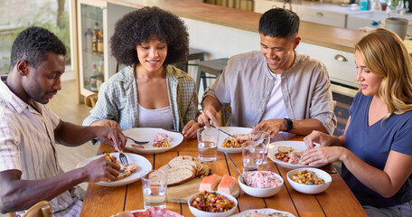Fototapeta na wymiar Group Of Multi-Racial Friends Sitting Around Table Enjoying Meal At Home Together
