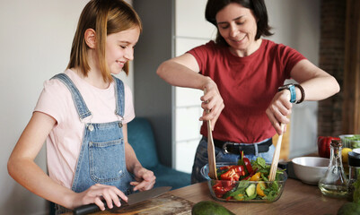 Beautiful Little Girl With Her Mother Cooking A Healthy Fresh Vegetable Salad In The Kitchen