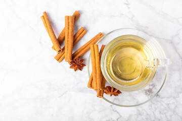 Fragrant hot tea with cinnamon stick and anise on a textured wooden background. A cup of hot tea...