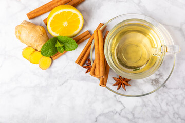 Fragrant hot tea with cinnamon stick and anise on a textured wooden background. A cup of hot tea with honey, lemon, mint and apples. Spicy tea with spices. Immunity tea. Health concept.Copy space.