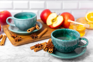 Obraz na płótnie Canvas Fragrant hot tea with cinnamon stick and anise on a textured wooden background. A cup of hot tea with honey, lemon, mint and apples. Spicy tea with spices. Immunity tea. Health concept.Copy space.