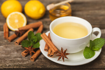 Fragrant hot tea with cinnamon stick and anise on a textured wooden background. A cup of hot tea...