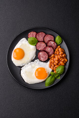English breakfast with fried eggs, bacon, beans, tomatoes, spices and herbs