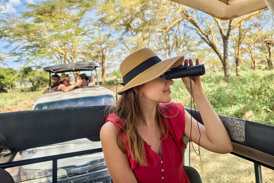 Girl with the binoculars against background of the nature. Observation of birds. Birdwatching. African safari by car with an open roof. Animal watching in the wild .