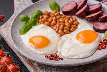English breakfast with fried eggs, bacon, beans, tomatoes, spices and herbs