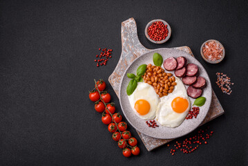 English breakfast with fried eggs, bacon, beans, tomatoes, spices and herbs
