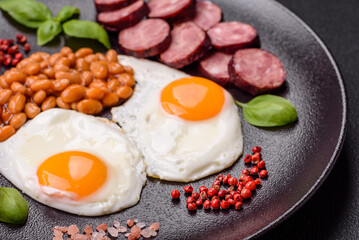 English breakfast with fried eggs, bacon, beans, tomatoes, spices and herbs