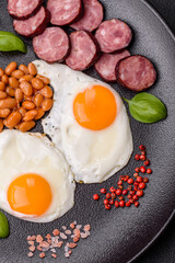 English breakfast with fried eggs, bacon, beans, tomatoes, spices and herbs