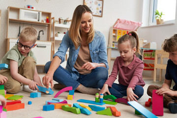 Children playing with toy blocks in the kindergarten - obrazy, fototapety, plakaty