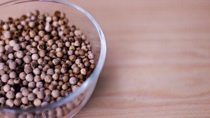 organic pepper dried white pepper corns in Indonesian in traditional asian glass bowl on wooden board. 