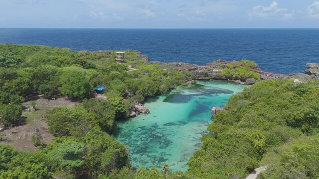 Weekuri Lagoon, Sumba island, Indonesia. A beautiful blue lake with a green forest in the background. The water is calm and clear, and the trees are lush and green