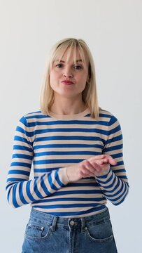 Displeased and unhappy Caucasian woman applauding with hands in shame, showing her boredom, hopelessness on white background. Vertical video.
