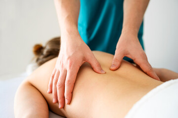 Girl during back massage in spa salon. Masseur hands doing care body therapy procedure for young woman wellness and relaxation. - obrazy, fototapety, plakaty